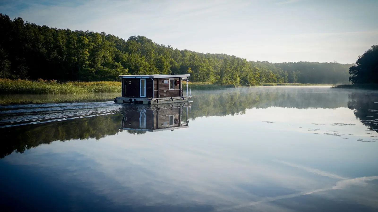 Schönes Revier in Brandenburg: Ein Hausboot fährt am frühen Morgen im Sonnenschein über die Havel. (Foto: Kay Nietfeld/dpa/dpa-tmn)