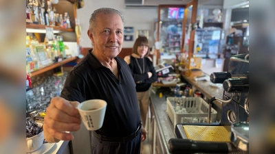 Orlando Paldino zeigt stolz eine Tasse Espresso für 70 Cent. Im Hintergrund steht seine Frau Rosina Furiati. (Foto: Christoph Sator/dpa)