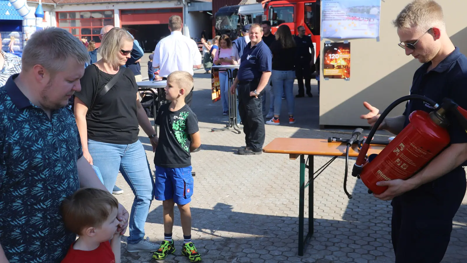 Wie geht man mit einem Feuerlöscher um? Tobias Lengdobler (rechts) weist Groß und Klein ein. (Foto: Oliver Herbst)