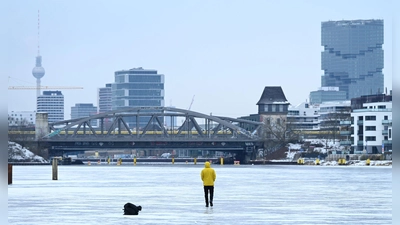 Ein Mann steht am Treptower Park in Berlin auf der zugefrorenen Spree. (Foto: Elisa Schu/dpa)