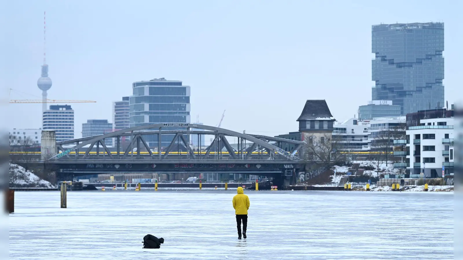 Ein Mann steht am Treptower Park in Berlin auf der zugefrorenen Spree. (Foto: Elisa Schu/dpa)