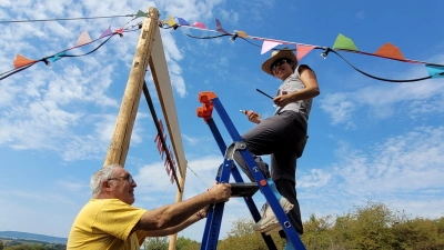 Eleni Martin aus dem P-Seminar ist zugleich Helferin auf dem Festival, genauso wie ihr Vater Uwe Martin. Gemeinsam haben sie die bunten Wimpel und die Lichterkette an den Seiten-Seilen des Torbogens montiert. (Foto: Nina Daebel)
