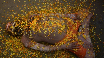 Bei einem hinduistischen Frühlingsfest in Indien liegt ein Sadhu mit Blütenblättern bedeckt auf der Straße.  (Foto: Prabhat Kumar Verma/ZUMA Press Wire/dpa)