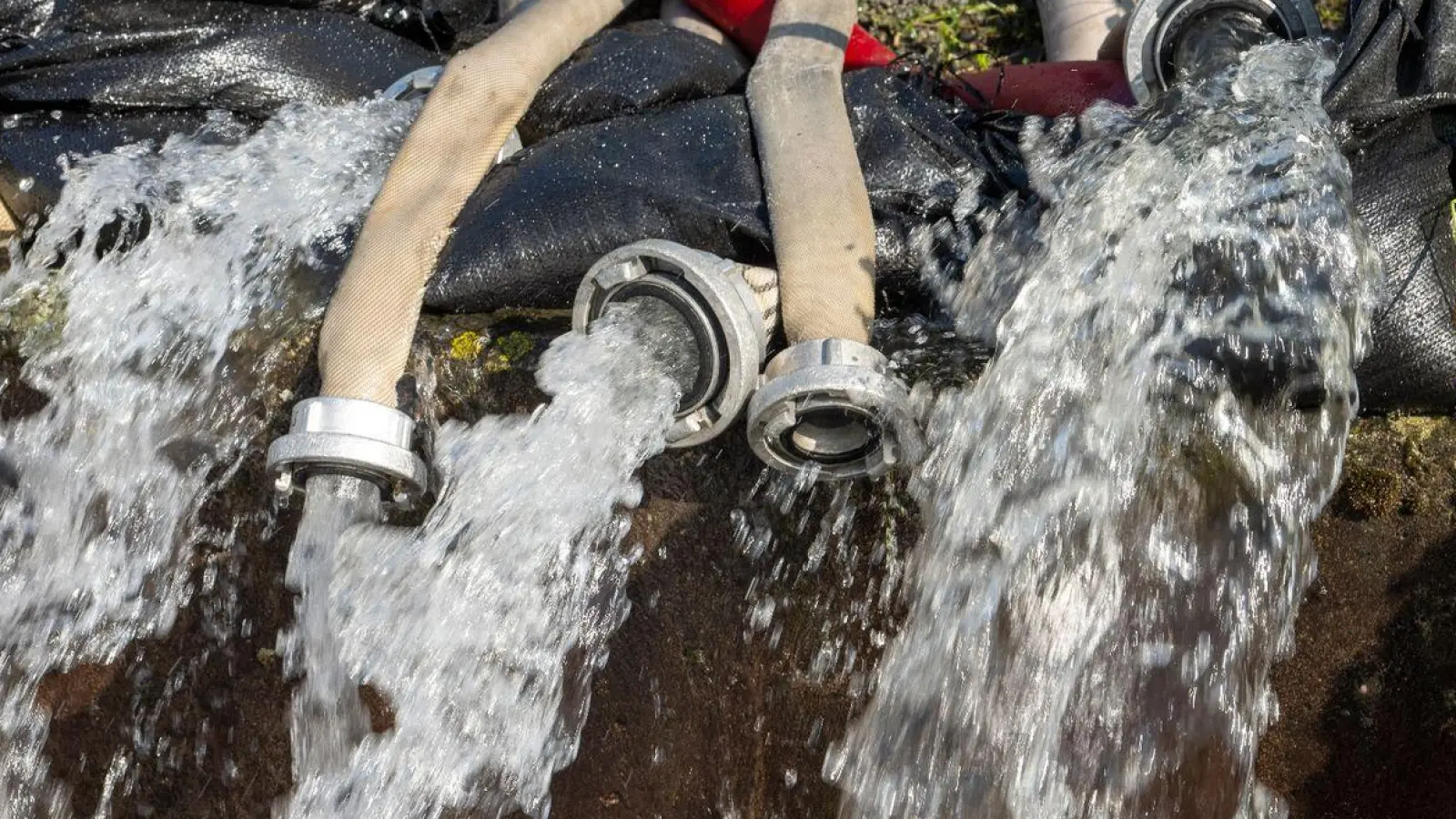 Aus zahlreichen Schläuchen fließt abgepumptes Wasser. In Bayern herrscht nach heftigen Regenfällen vielerorts weiter Land unter. An den westlichen Donauzuflüssen sinken die Pegel langsam. (Foto: Stefan Puchner/dpa)