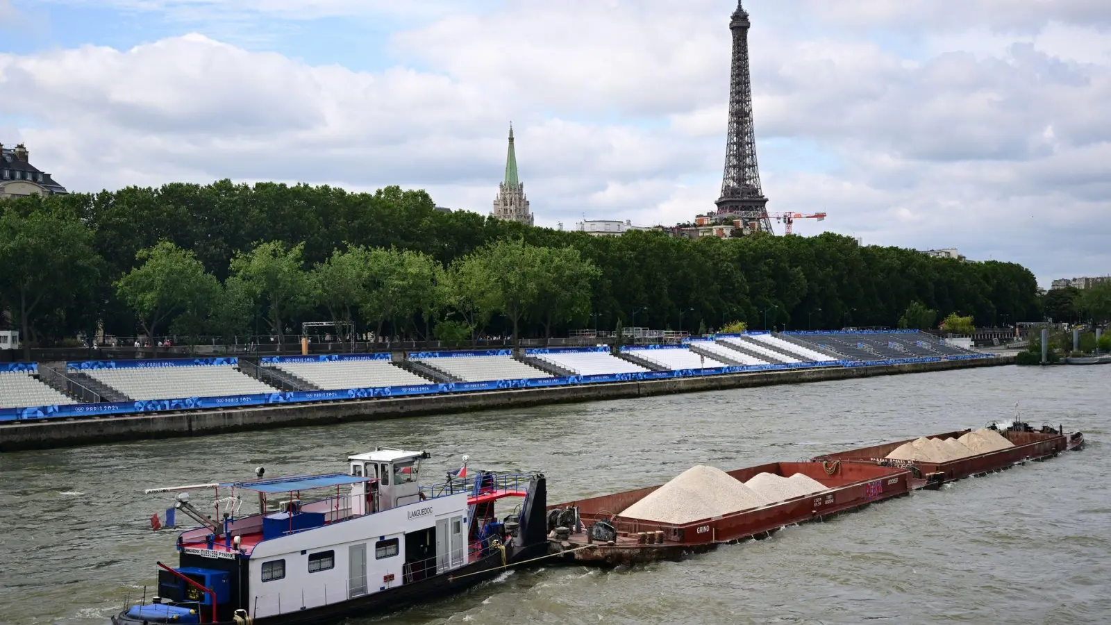 Keine Filmszene, sondern ein Foto aus dem Sommer während Olympia. Ein Schiff passiert Tribünen, im Hintergrund ist der Eiffelturm zu sehen. Im Netflix-Hit „Im Wasser der Seine“ treibt dagegen ein Hai sein Unwesen im Pariser Gewässer. (Archivbild) (Foto: Sina Schuldt/dpa)