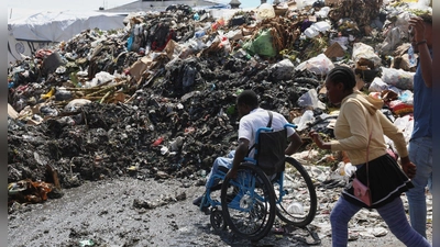 Ein Mann im Rollstuhl versucht, die Straße zu überqueren, vorbei an Müll im Viertel Petion-ville in Port-au-Prince, Haiti. (Foto: Odelyn Joseph/AP/dpa)