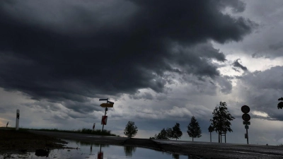 Dichte Regenwolken spiegeln sich in einer Pfütze. (Foto: Karl-Josef Hildenbrand/dpa/Symbolbild)