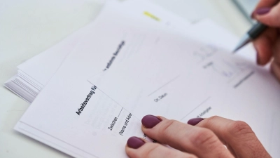 Eine Frau unterschreibt einen Arbeitsvertrag. (Foto: Annette Riedl/dpa)