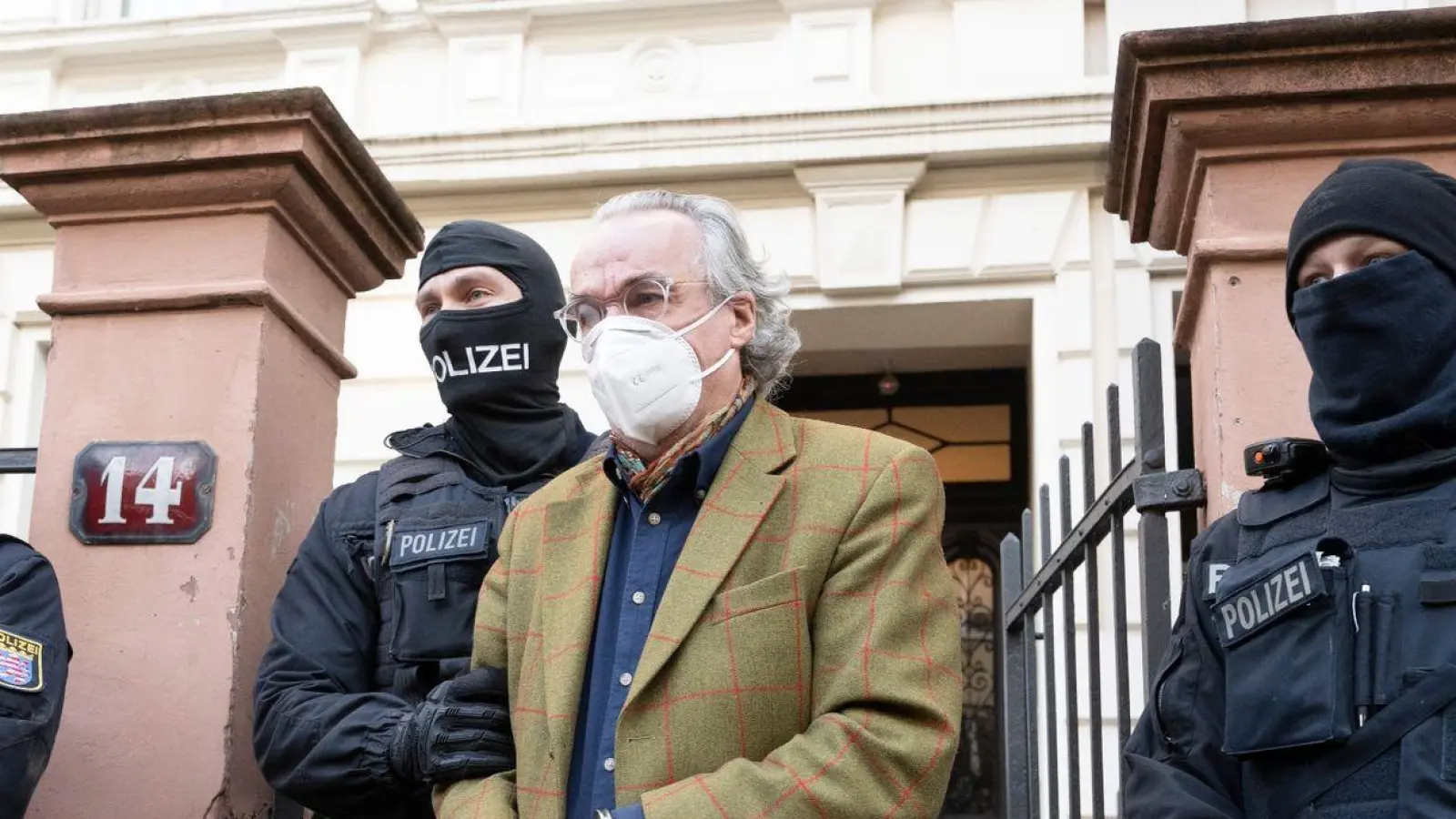 Bei einer Razzia gegen „Reichsbürger“ führen vermummte Polizisten nach der Durchsuchung eines Hauses Heinrich XIII. Prinz Reuß (2.v.r.) zu einem Polizeifahrzeug. (Foto: Boris Roessler/dpa)