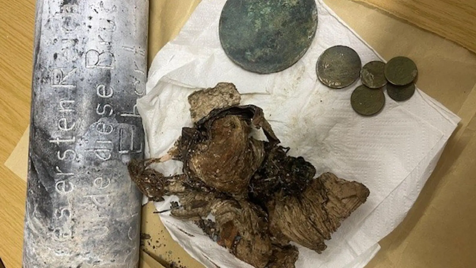 Silber- und Kupfermünzen, ein Zeitungsartikel und Fotos wurden seit dem beim Bau einer Brücke in Hof im Jahr 1928 in einer Zeitkapsel aufbewahrt. Nun sind die Gegenstände beim Abriss des Bauwerks wiedergefunden worden. (Foto: -/Stadt Hof/dpa)