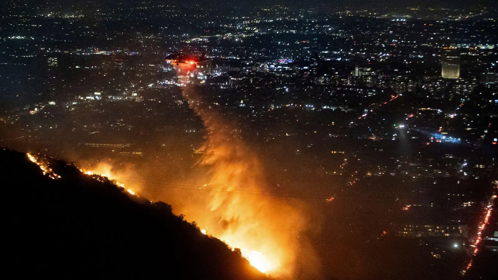 Die Löscharbeiten in den berühmten Hollywood Hills dauern an, die Behörden geben aber leichte Entwarnung. (Foto: Ethan Swope/AP/dpa)