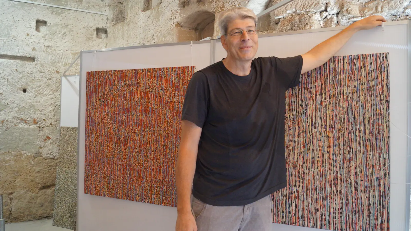 Ausstellungskurator Manfred Hönig vor Werken der verstorbenen Malerin Gabriela Dauerer. Diese sind in der Scheune der Kunstmühle zu finden. (Foto: Nicole Gunkel)