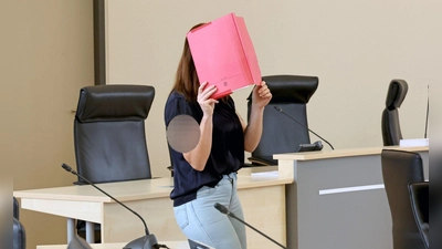 Die Angeklagte betritt den Gerichtssaal mit rotem Aktendeckel vor dem Gesicht. (Foto: A7120 Bernd Wüstneck/dpa)