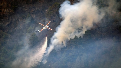 Ein Hubschrauber wirft Wasser auf die Flammen, während sich das Feuer durch den Wald in Richtung der Stadt Pinolere ausbreitet. (Foto: Arturo Rodriguez/AP/dpa)