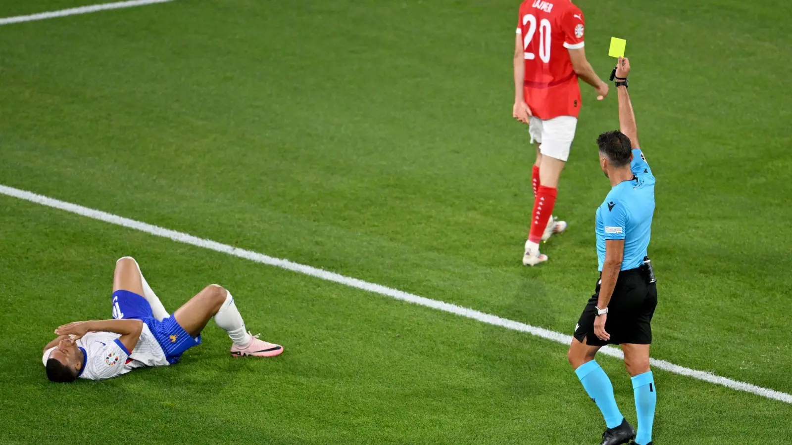 Schiedsrichter Jesús Gil Manzano zeigt dem Österreicher Konrad Laimer (m) Gelb nach einem Foul an Kylian Mbappé. (Foto: Fabian Strauch/dpa)