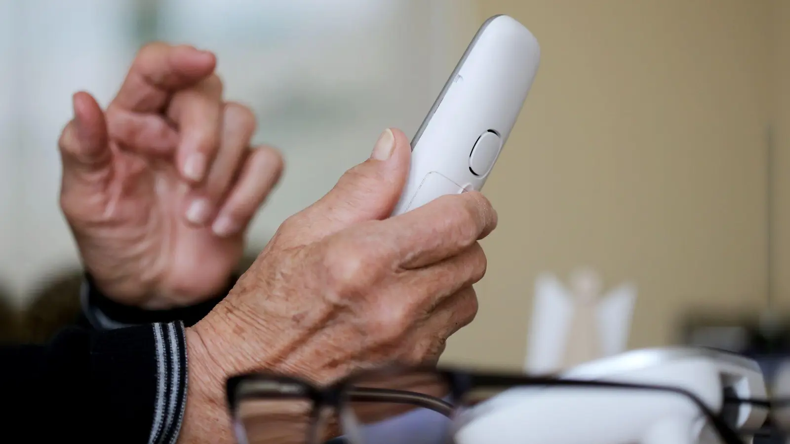 Ein älterer Mensch greift zum Telefon. (zu dpa: «Betrüger in U-Haft - Polizei sucht weiter nach teuren Uhren») (Foto: Roland Weihrauch)