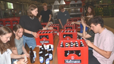 Fast im Akkord klebten etliche Absolventinnen und Absolventen des Friedrich-Alexander-Gymnasiums 2300 Etiketten mit der Aufschrift „Abi-Bier 2024“. (Foto: Anita Dlugoß)