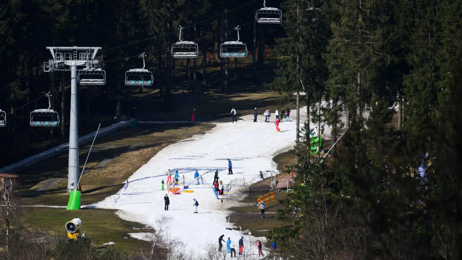 Der visualisierte Alptraum jedes Skiurlaubers: Schneemangel und damit nur schmale weiße Pistenteppiche auf braun-grünen Hängen. (Foto: Robert Michael/dpa/dpa-tmn)