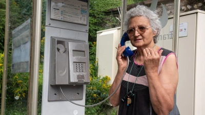 Marie-Claude König nimmt in Murbach einen Anruf entgegen. In der Telefonzelle im Elsass rufen Menschen aus der ganzen Welt an. (Foto: Florian Bodenmüller/SWD - Südwestdeutsches Mediennetzwerk GmbH/dpa)