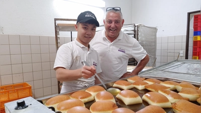 Zur Kerwa gehören in Franken Küchle: Hung Nguyen Van dreht das goldbraune Gebäck unter Gerhard Merkels Aufsicht. (Foto: Katrin Merklein)