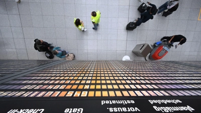 Fluggäste stehen unter einer Anzeigentafel im Terminal 2. Der Flughafen München erwartet zu Beginn der Pfingstferien Hunderttausende Fluggäste. (Foto: Felix Hörhager/dpa)