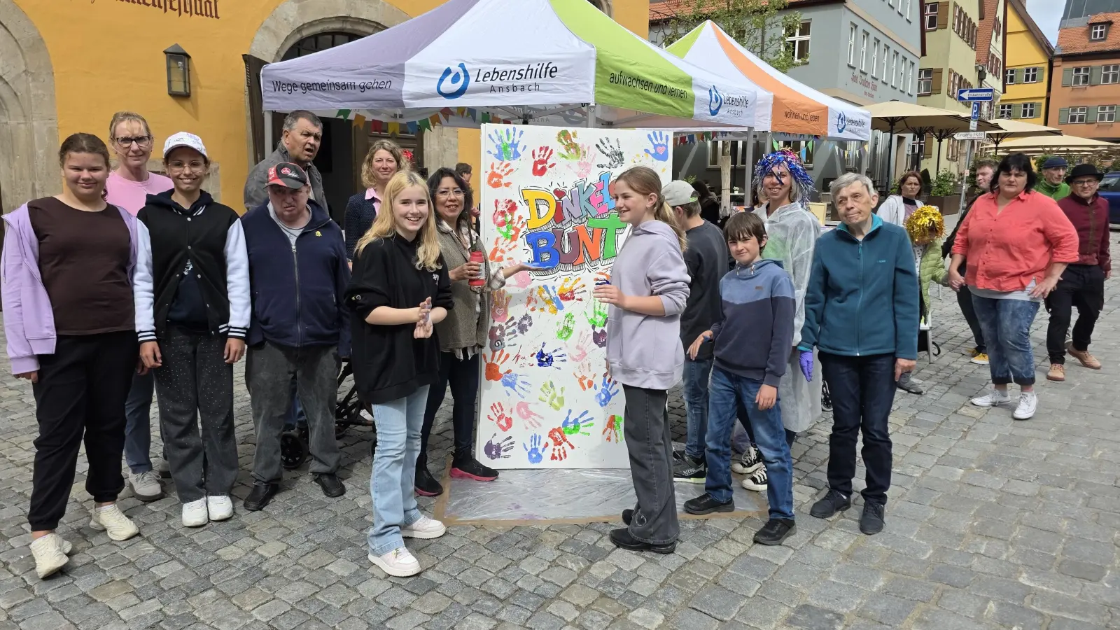 Das Kunstwerk nimmt Gestalt an: Projektverantwortliche, Heimbewohnende sowie Schülerinnen und Schüler freuen sich über die vielen bunten Hände auf der Leinwand. (Foto: Markus Weinzierl)