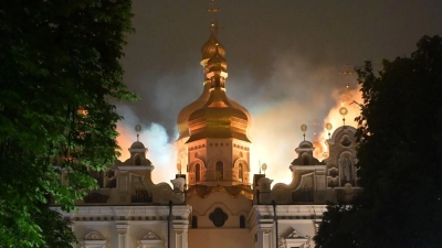 Flammen züngeln aus dem Dach unter den vergoldeten Kuppeln der Mariä-Entschlafens-Kathedrale.  (Foto: Danylo Antoniuk/AP/dpa)