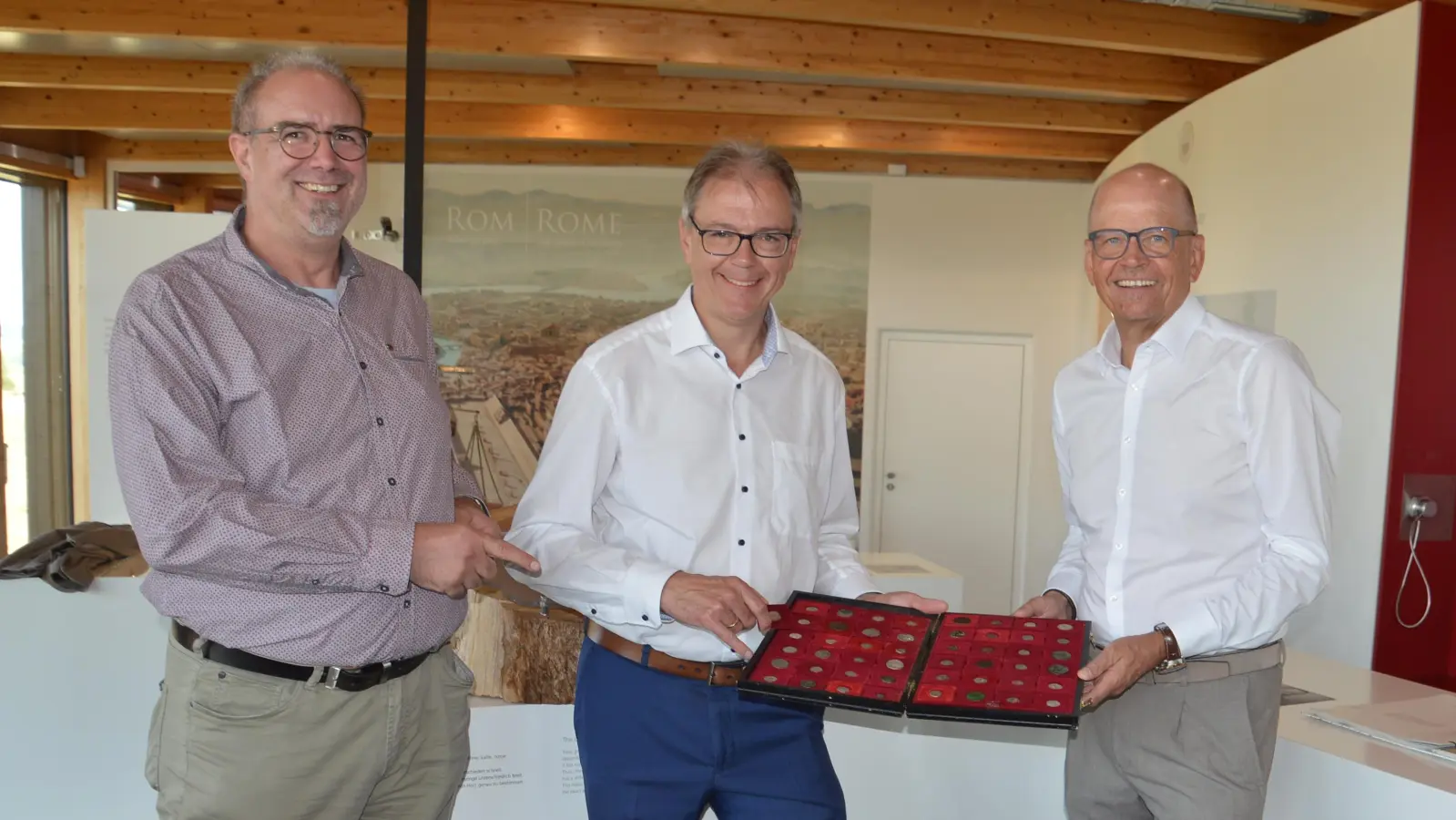 Einblicke in den Münzkoffer gewährte Museumsleiter Dr. Matthias Pausch (links) bei der Spendenübergabe der Sparkassenstiftung Ansbach durch Werner Frieß (rechts) an den Vorsitzenden des Fördervereins Römerpark Ruffenhofen, Bernd Großmann (Mitte). (Foto: Peter Tippl)