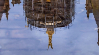 Das Schweriner Schloss spiegelt sich in einer Regenpfütze – graues, kühles und regnerisches Wetter zeigt den norddeutschen Sommer von seiner unfreundlichen Seite. (Foto: Jens Büttner/dpa)