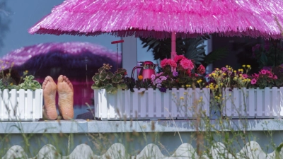 Time to relax - Frau liegt auf ihrem Balkon unter einem pinken Sonnenschirm in Betzenweiler (Foto: Thomas Warnack/dpa)