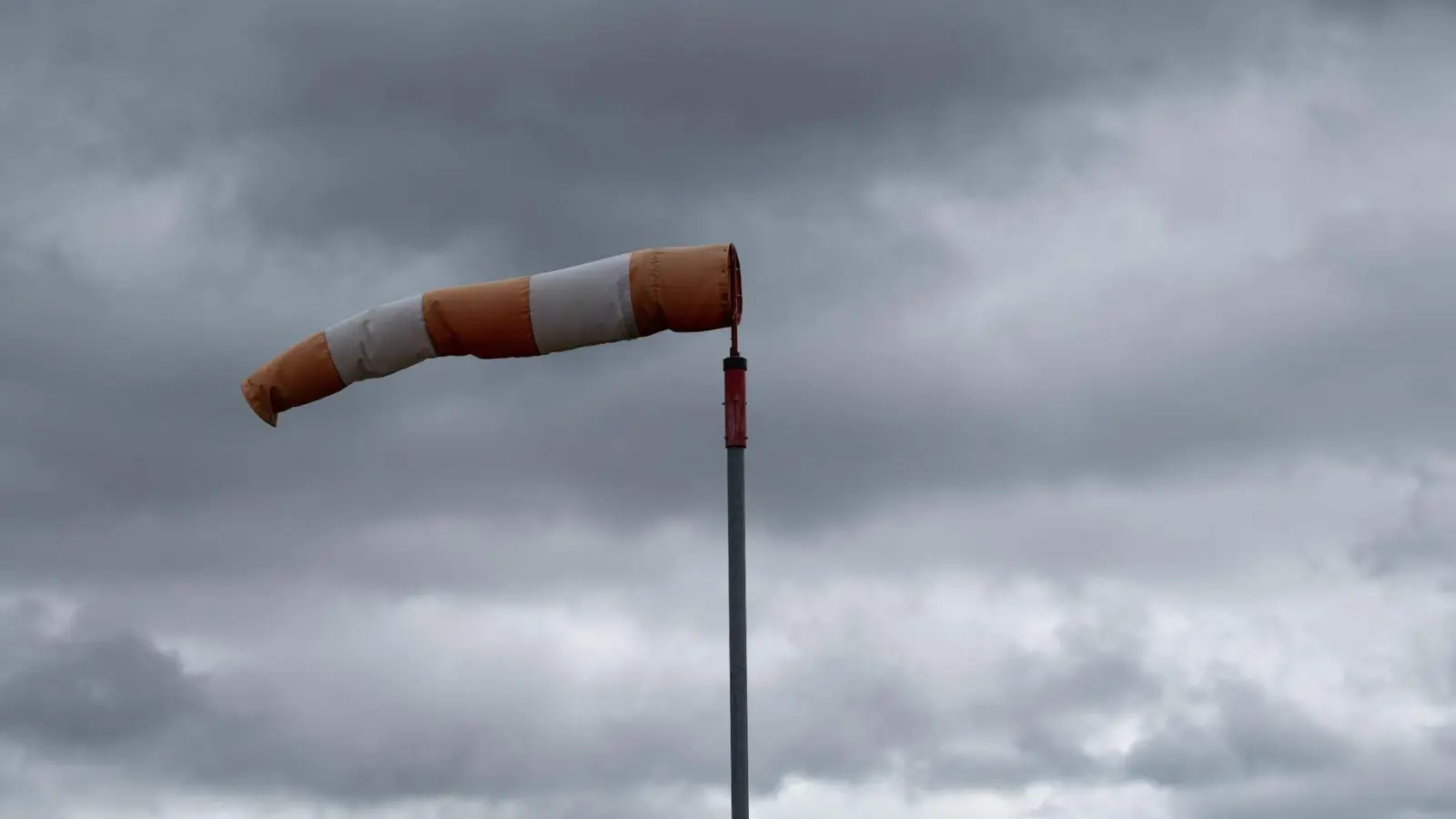 Ein Windsack weht bei stürmischem Wetter im Wind. (Symbolbild: Silas Stein/dpa)