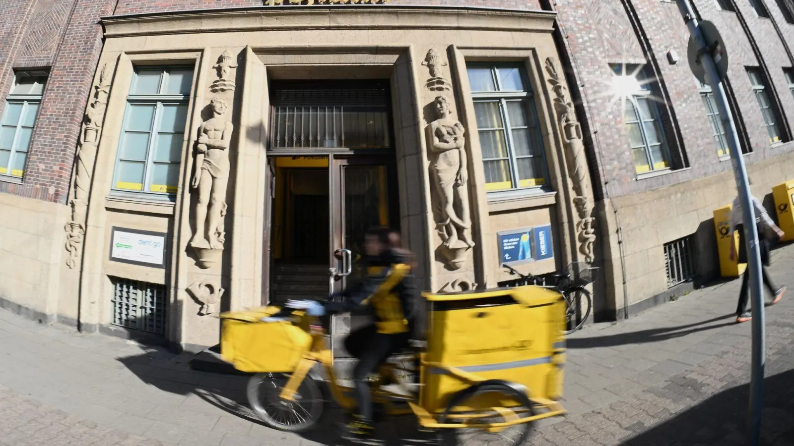 Eine Briefträgerin fährt an einer Postfiliale vorbei - vielleicht ist auch sie eine Beamtin? (Foto: Wolf von Dewitz/dpa)
