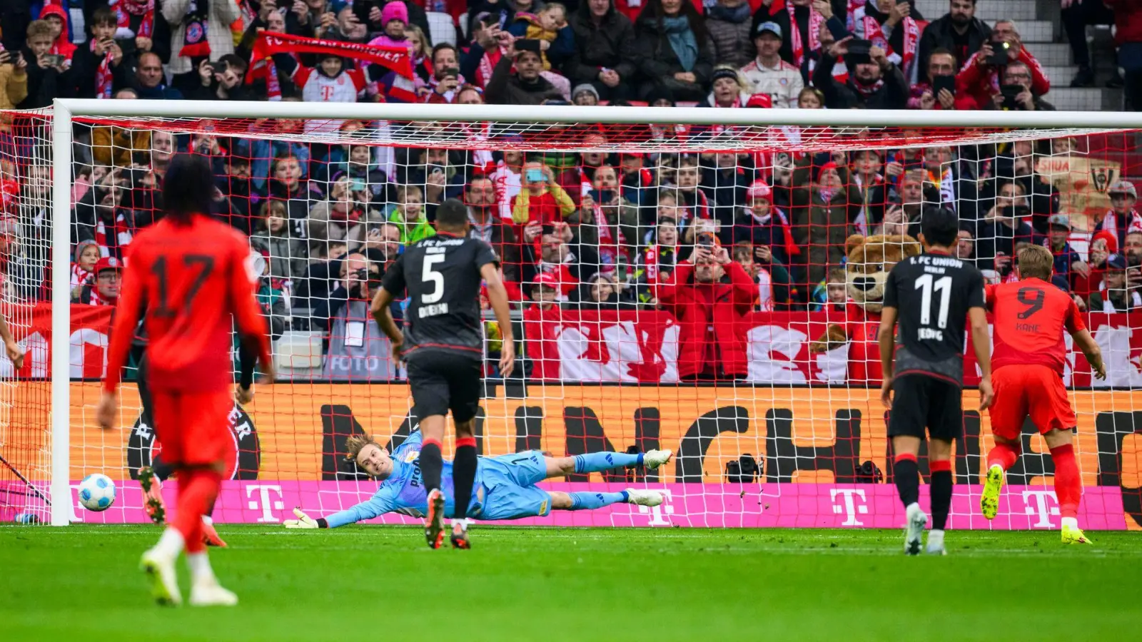 Harry Kane (r) schießt den Elfmeter in die Ecke, die ihm Union-Torwart Frederik Rönnow anzeigte. (Foto: Tom Weller/dpa)