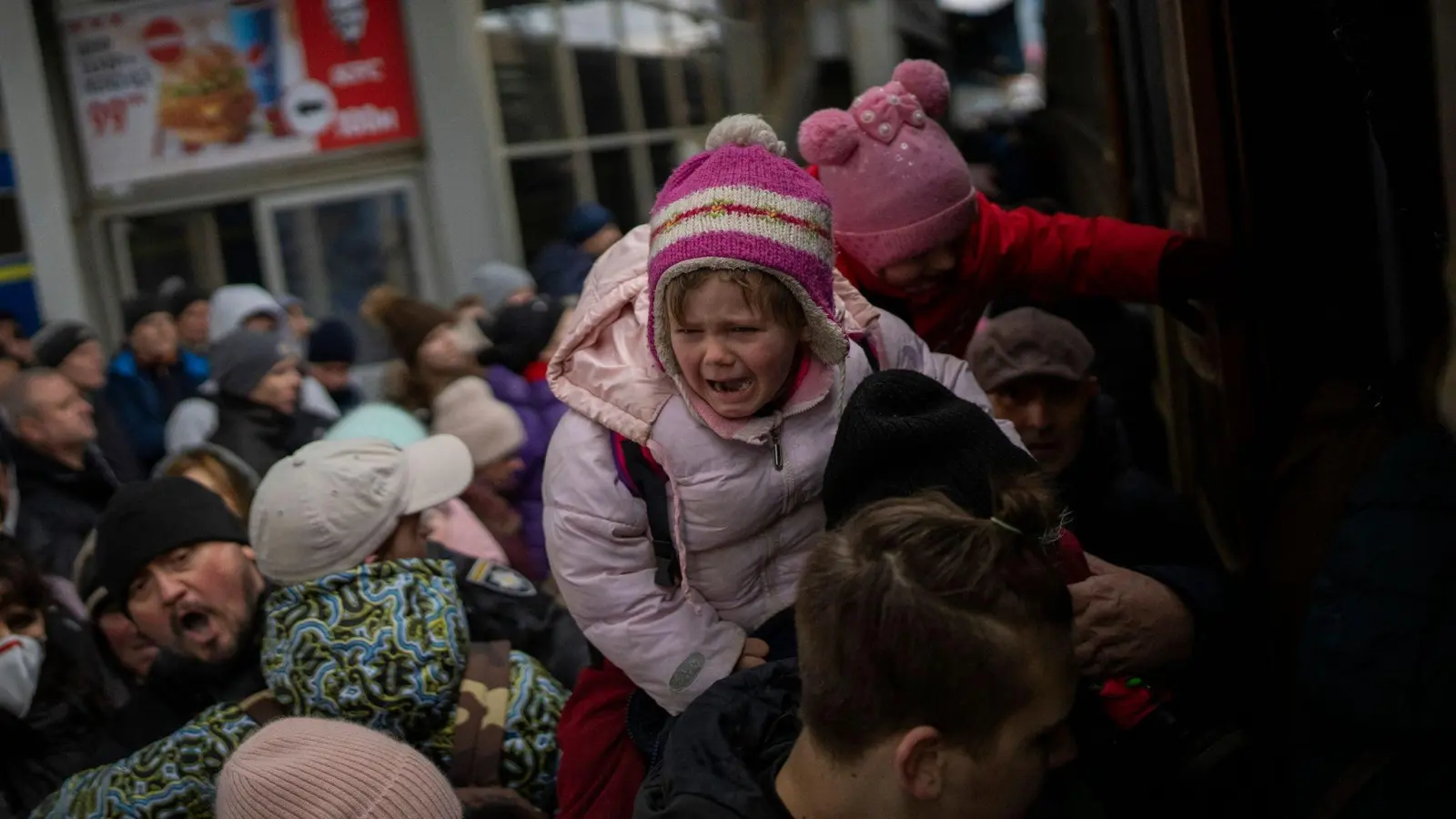 Menschen tragen ihre Kinder und versuchen am Bahnhof von Kiew in einen Zug nach Lwiw zu steigen. (Foto: Emilio Morenatti/AP/dpa)