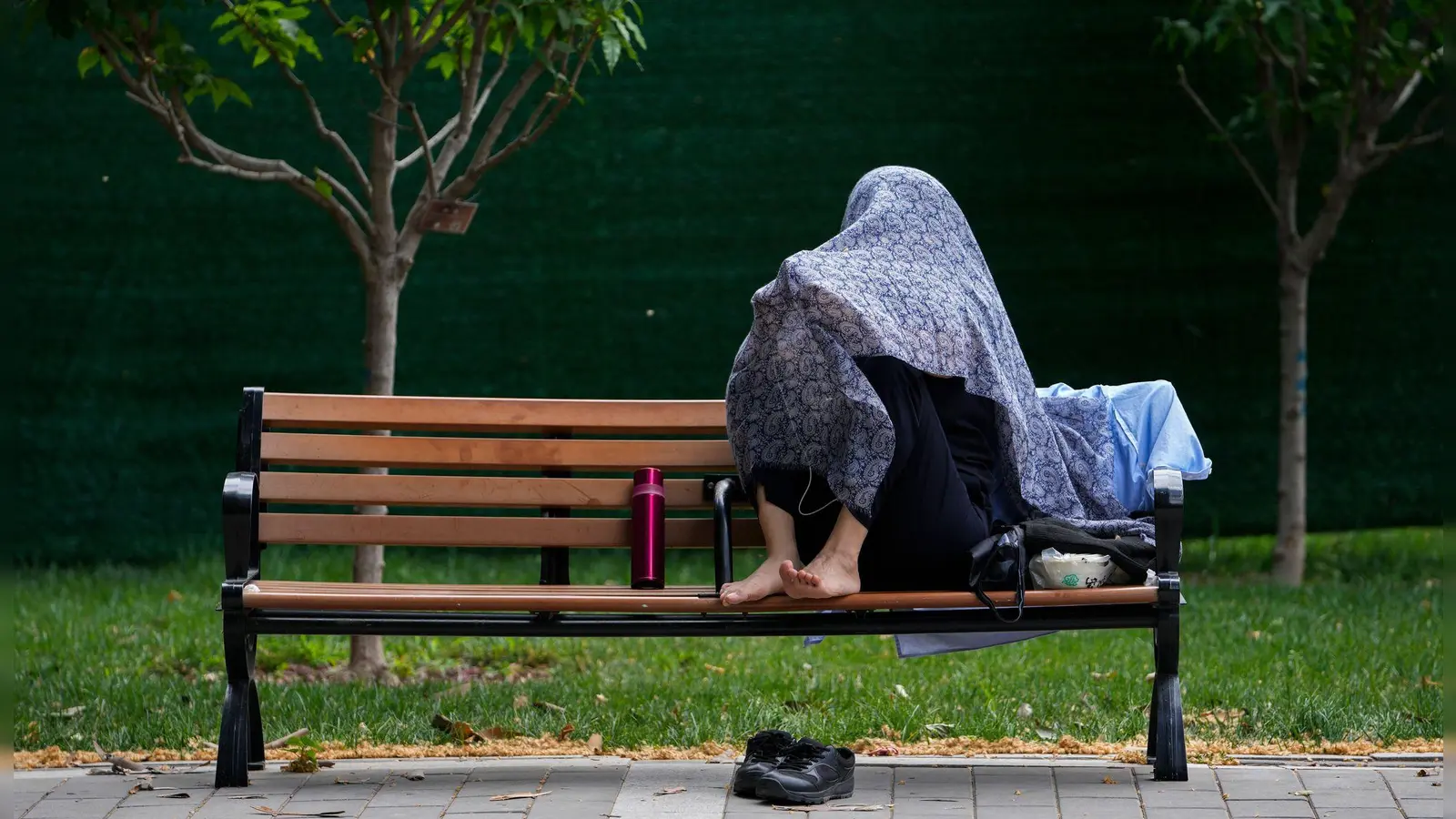 Eine Frau in China schützt sich mit einem Tuch vor der Sonne. (Foto: Andy Wong/AP)