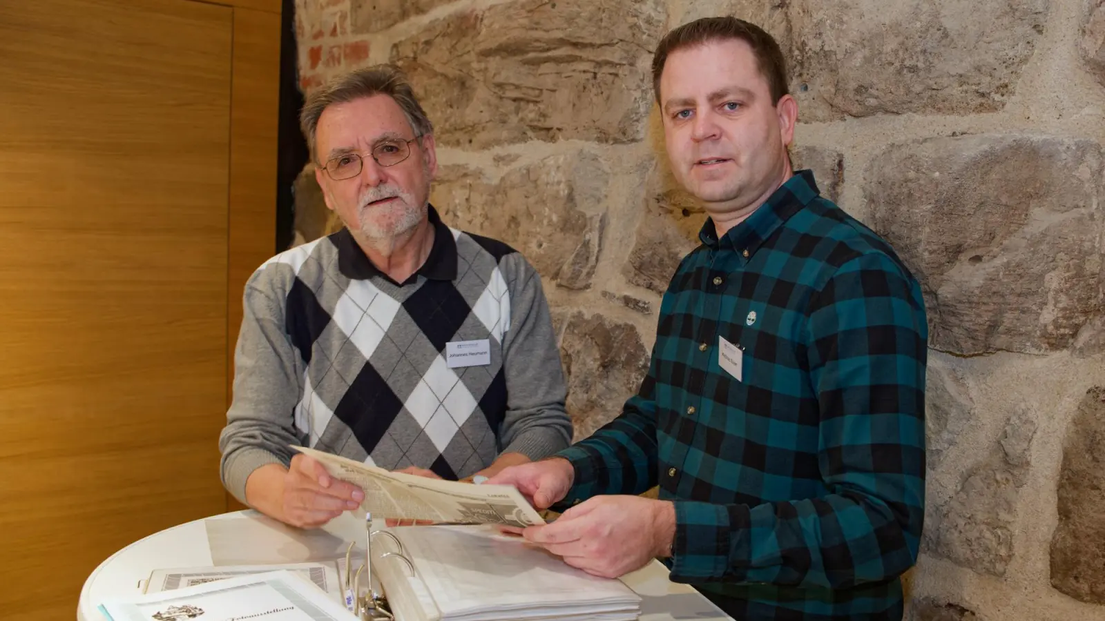 Johannes Heumann (links) und Matthias Bayer vom Film- und Fotoclub Herrieden im Ratssaal des Stadtschlosses beim Blättern in Archivalien. In Händen halten sie einen Beitrag aus der Fränkischen Landeszeitung vom 2. Januar 1993, der über die 20. Ausstellung berichtet. (Foto: Friedrich Weigel)