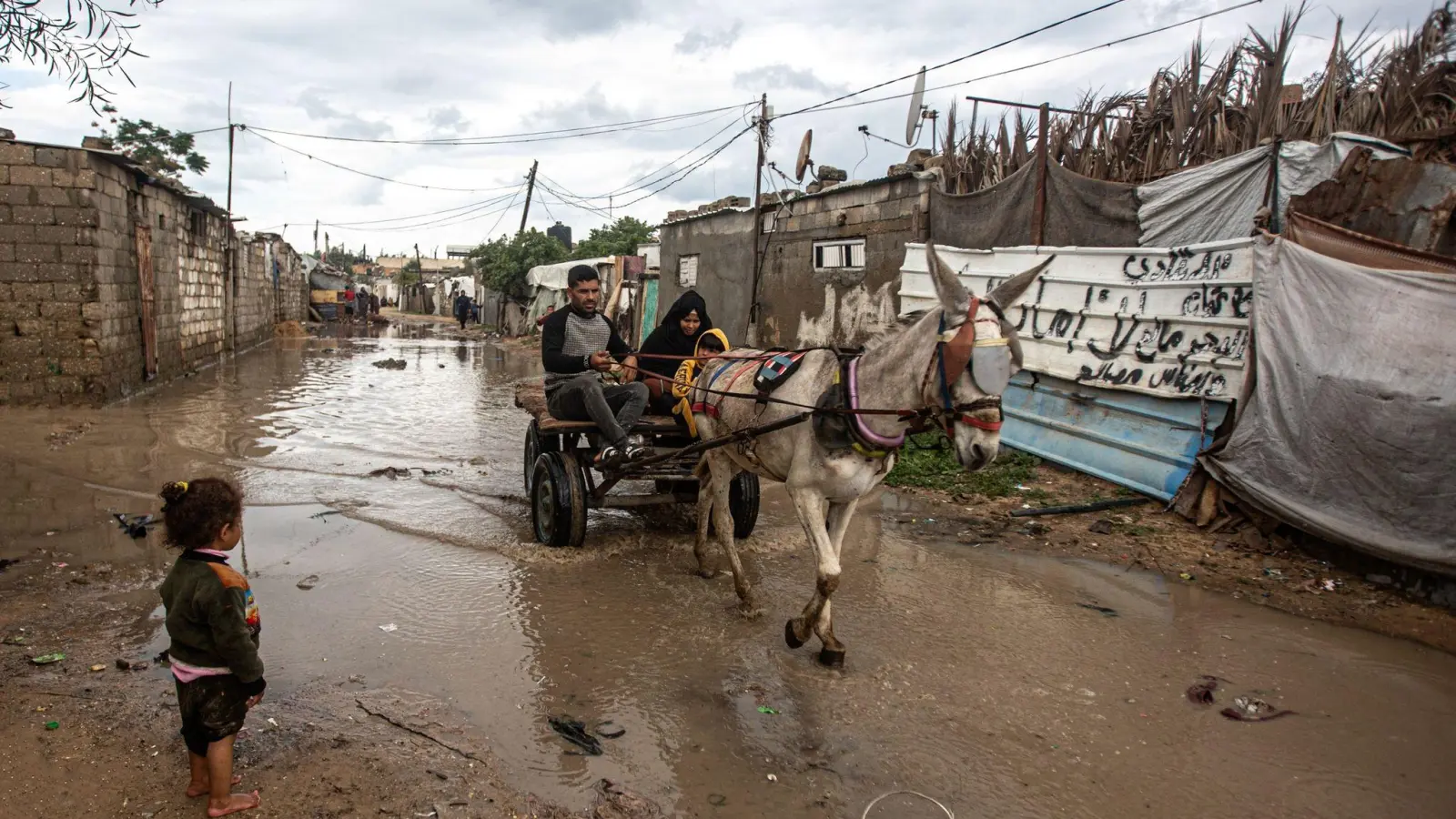 Eine Familie fährt mit einer Kutsche über einen überschwemmten Weg. Schwere Regenfälle und Überschwemmungen beeinträchtigen das tägliche Leben der Palästinenser in der Stadt Khan Yunis im südlichen Gazastreifen. (Foto: Yousef Mohammed/IMAGESLIVE via ZUMA Press Wire/dpa)