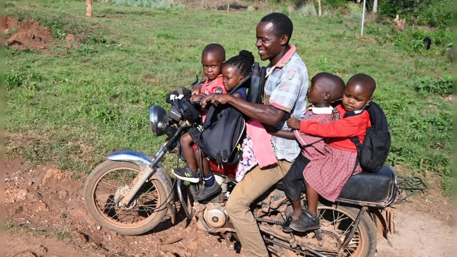 Ein Vater holt seinen Sohn und drei Nachbarskinder mit dem Boda Boda genannten Mopedtaxi ab – ein weit verbreitetes Verkehrsmittel in Uganda. (Foto: Wolfgang Grebenhof)