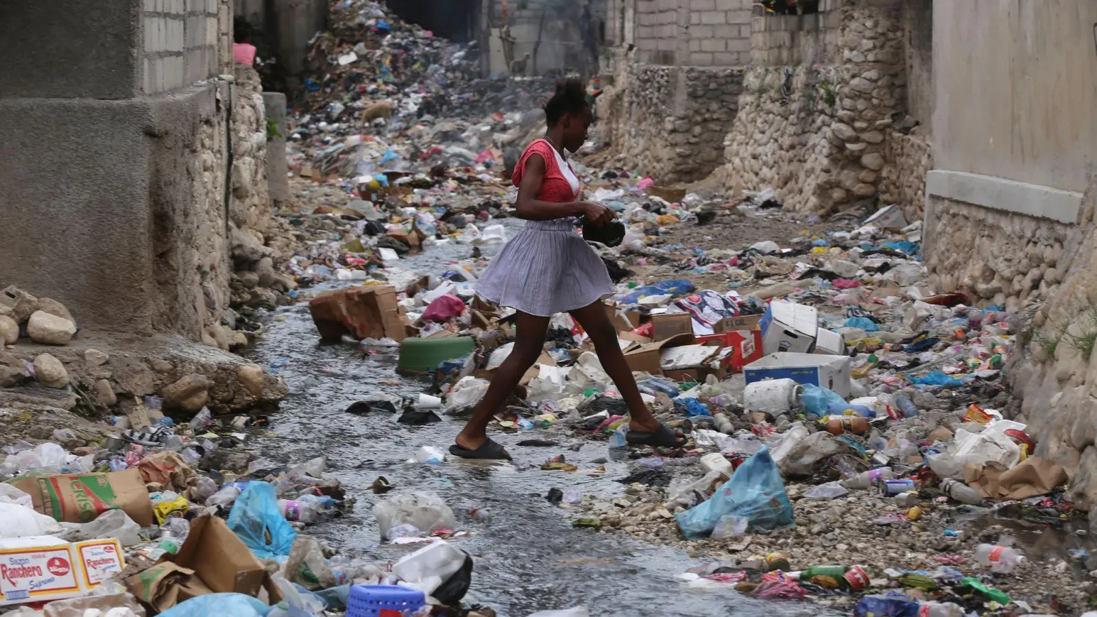 Ein Mädchen geht durch eine mit Müll gefüllte Häuserschlucht in Port-au-Prince. Bewaffnete Gruppen entführen dort zunehmend Kinder und Frauen - in den meisten Fällen zu finanziellen oder taktischen Zwecken. (Foto: Odelyn Joseph/AP)