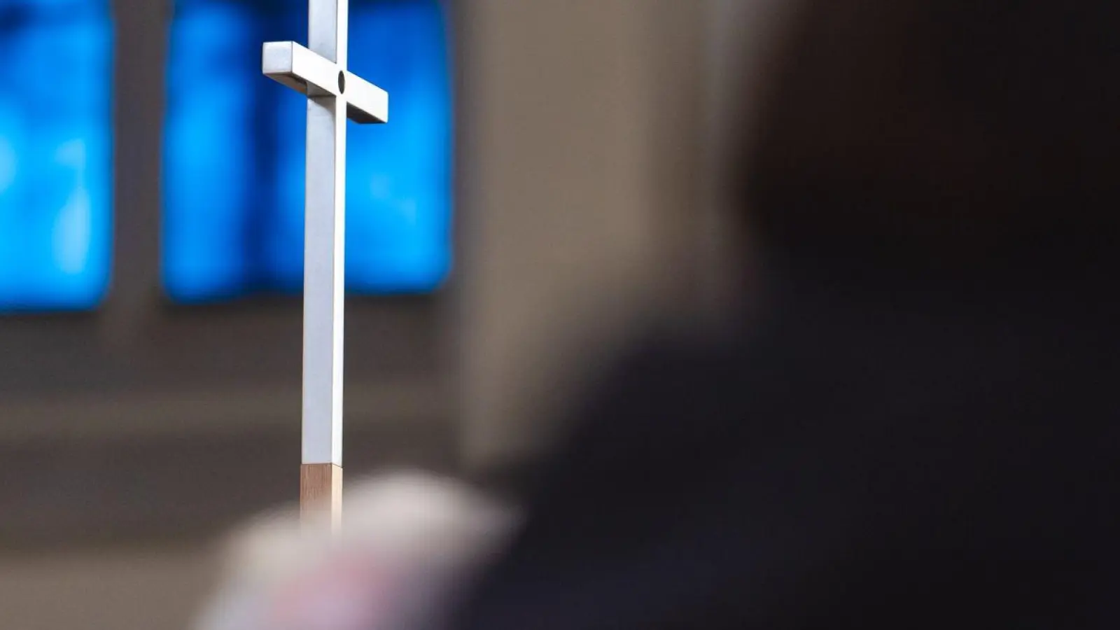 Ein christliches Kreuz wird während einer Solidaritätsaktion vom hereinfallenden Tageslicht angeleuchtet. (Foto: Nicolas Armer/dpa)