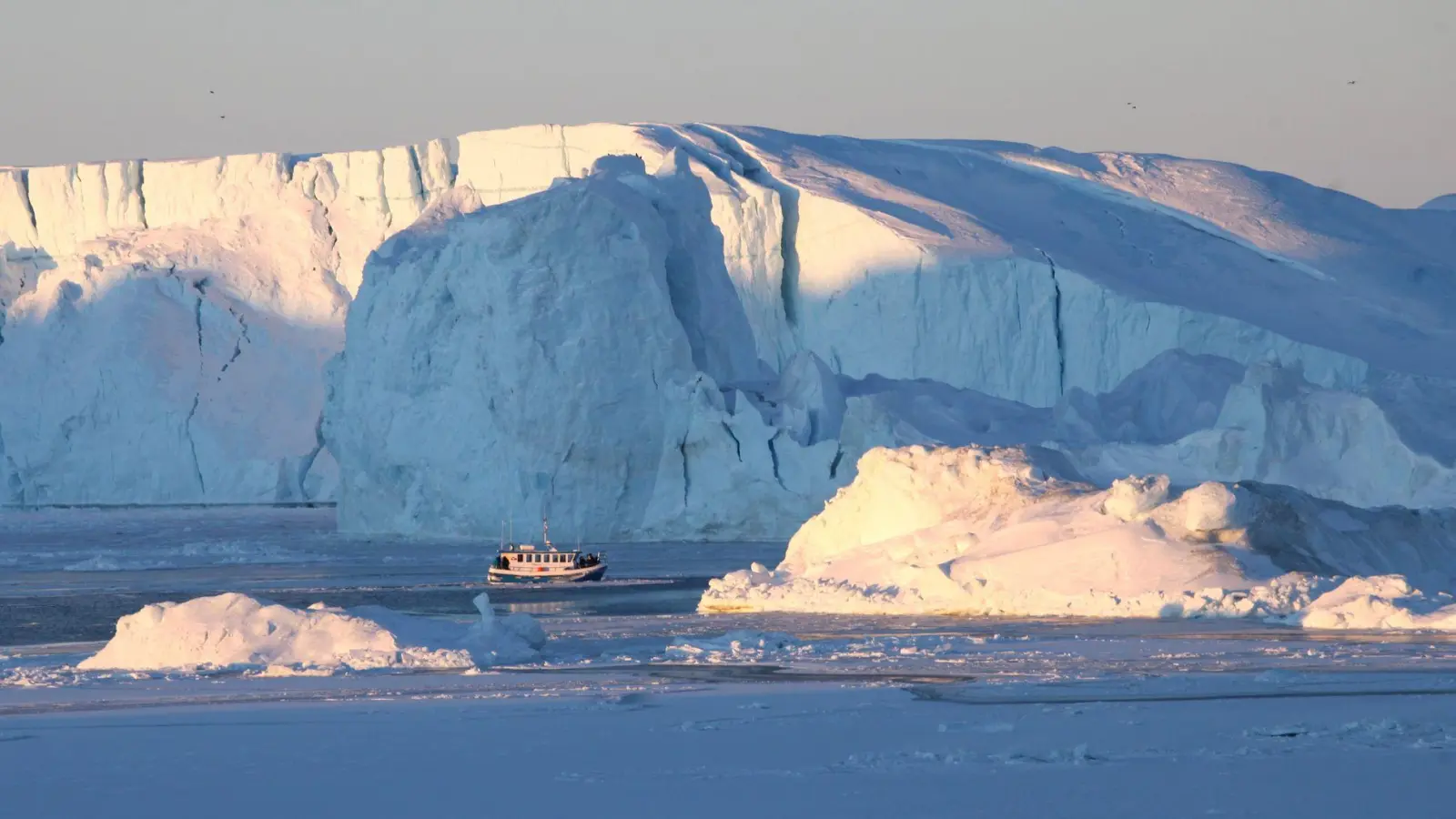 Ein Schiff mit Touristen fährt im Ilulissat-Eisfjord im Westen von Grönland an Eisbergen vorbei. (Foto: Steffen Trumpf/dpa-tmn)