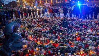 Menschen stehen vor der Johanniskirche in Magdeburg, wo ein Gedenkort eingerichtet und Blumen und Kerzen niedergelegt wurden. (Foto: Klaus-Dietmar Gabbert/dpa)