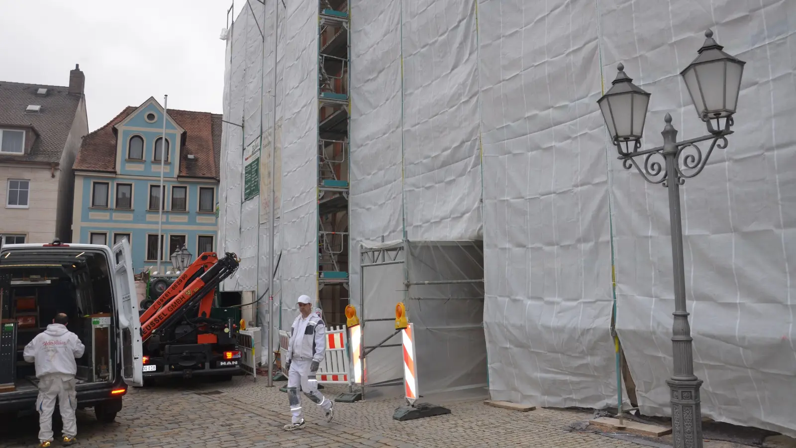 Voraussichtlich bis zum 12.Juni wird das Neustädter Rathaus noch verhüllt bleiben, dann soll die Sanierung der zum Marktplatz gewandten Fassade abgeschlossen sein. Die Aufhübschung des Teilbereichs zur Bamberger Straße hin ist für den Spätsommer vorgesehen. (Foto: Patrick Lauer)