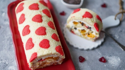 Für die Biskuitrolle wird auf die roten Herzchen aus dem Spritzbeutel heller Teig gestrichen und dann gebacken. (Foto: Mareike Pucka/biskuitwerkstatt.de/dpa-tmn)