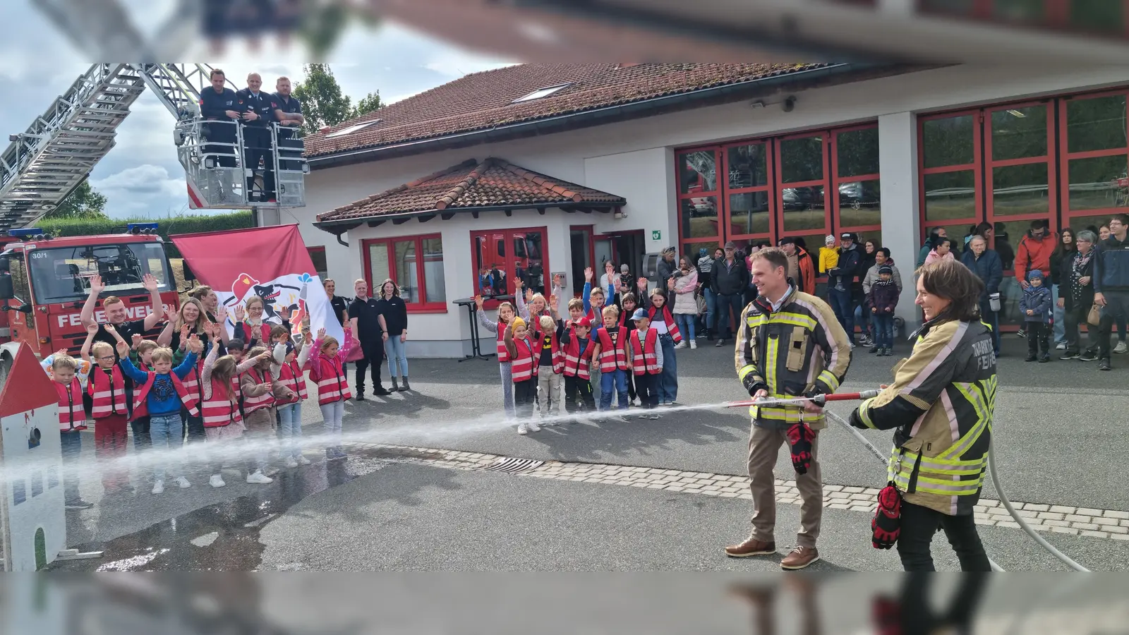 Bürgermeisterin Sandra Winkelspecht und Landrat Dr. Christian von Dobschütz (von rechts) bei der ersten „Lösch-Lektion“ für die Kinder der neuen Kinderfeuerwehr – unter dem wachsamen Augen zahlreicher Kinder und etlicher Aktiver. (Foto: Rainer Weiskirchen)