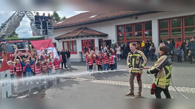 Bürgermeisterin Sandra Winkelspecht und Landrat Dr. Christian von Dobschütz (von rechts) bei der ersten „Lösch-Lektion“ für die Kinder der neuen Kinderfeuerwehr – unter dem wachsamen Augen zahlreicher Kinder und etlicher Aktiver. (Foto: Rainer Weiskirchen)