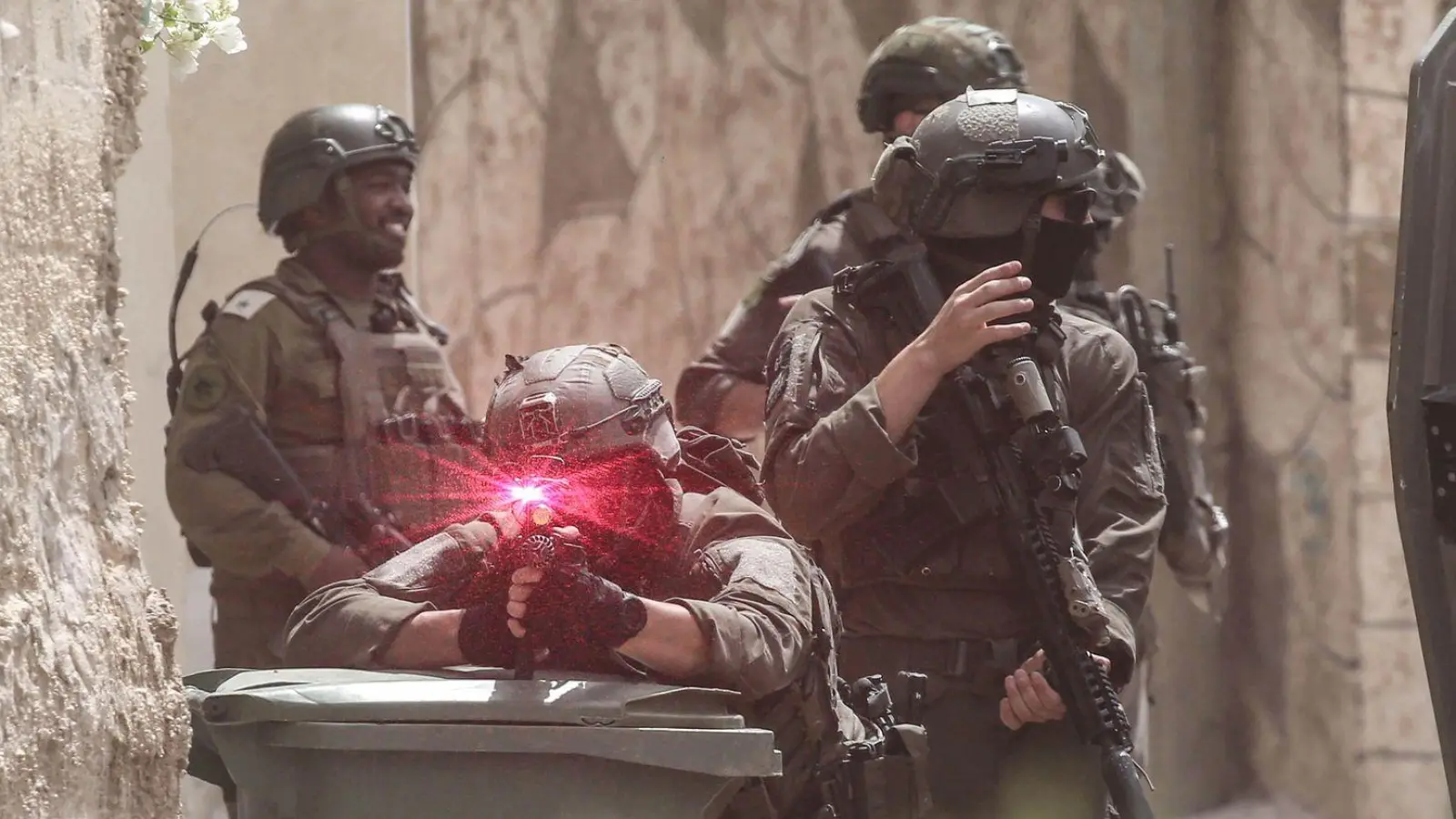 Israelische Soldaten gehen während einer Militäroperation im Norden des besetzten Westjordanlandes in Stellung. Ein Soldat zielt auf den Fotografen, man sieht die Laserzieleinrichtung leuchten. Die israelische Armee hat während einer Militäroperation in der Stadt Tamun ein Gebäude umstellt und fünf Palästinenser getötet, die sich darin verbarrikadiert hatten. (Foto: Nasser Ishtayeh/SOPA Images via ZUMA Press Wire/dpa)