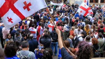 Demonstrantinnen und Demonstranten schwenken vor dem Parlamentsgebäude in Tiflis georgische Nationalflaggen. (Foto: Shakh Aivazov/AP/dpa)