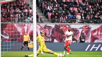 Bremens Torwart Mio Backhaus (l, Werder Bremen) und Ridle Baku (RB Leipzig) schauen dem Ball hinterher. Backhaus verhinderte mit seinen Paraden einen frühen Rückstand der Gäste in Leipzig. (Foto: Jennifer Brückner/dpa)