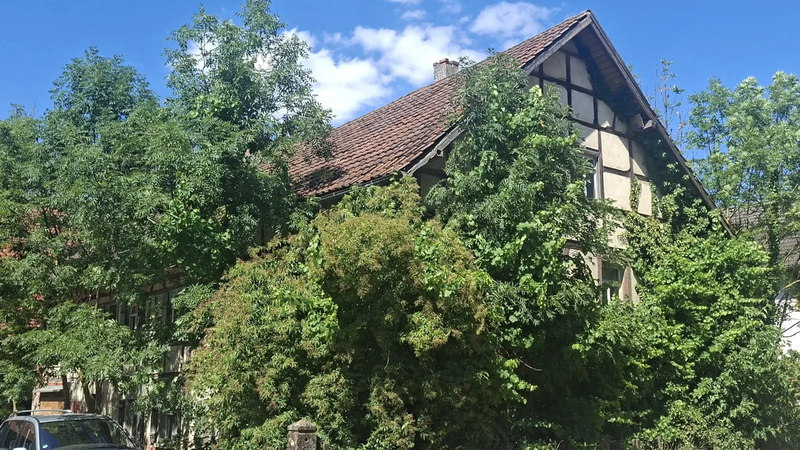Das Anwesen in der Mönchstraße, das die Gemeinde geerbt hat: links Scheune, Mitte altes Haus, rechts, etwas versteckt hinter den Bäumen, das neuere Haus. (Foto: Gertraud Nöth)